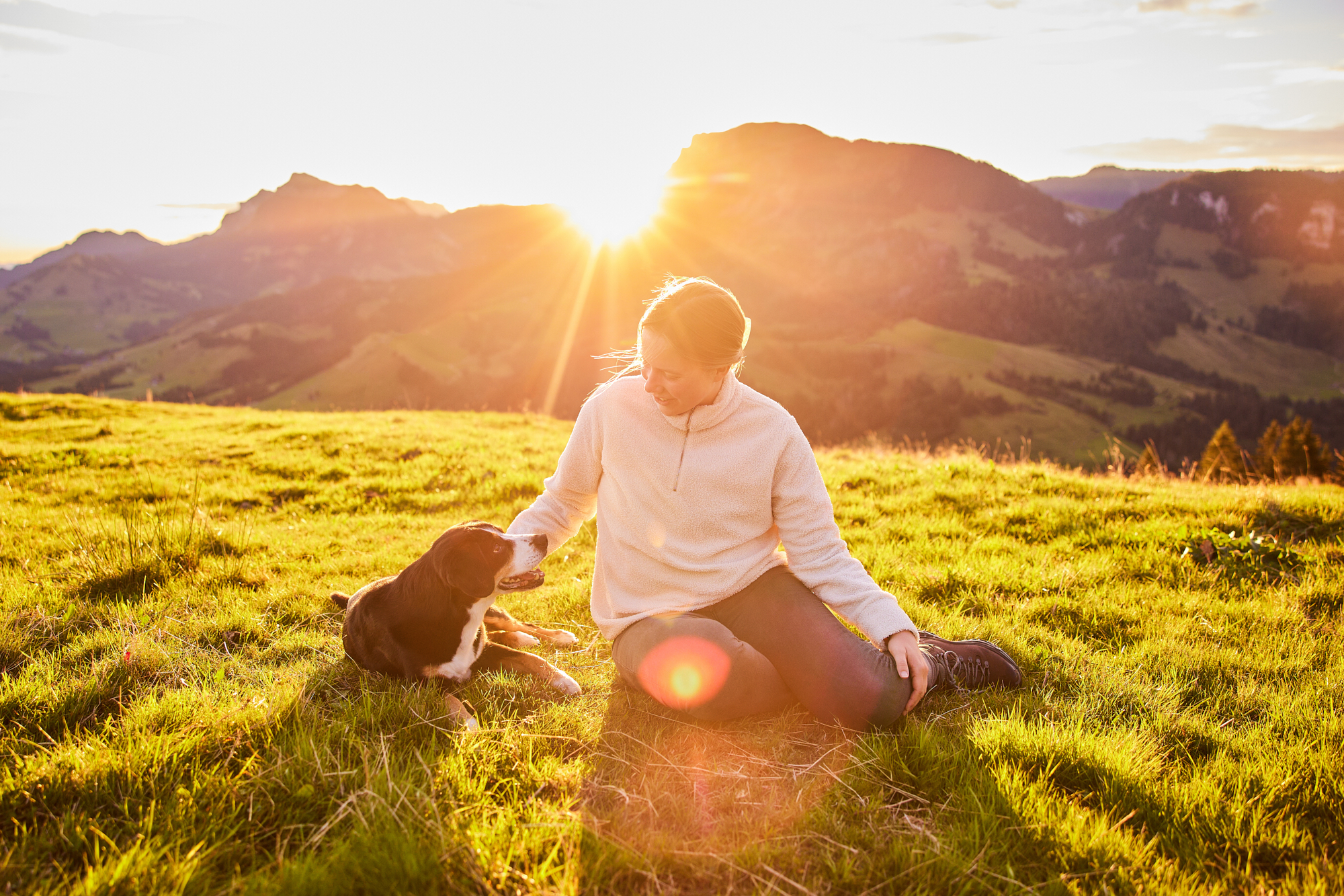 Entlebucher Sennenhund mit Hundebesitzerin bei einem Fotoshooting in Entlebuch in der Schweiz im Sonnenaufgang, professionelles Hunde-Fotoshooting in der Natur