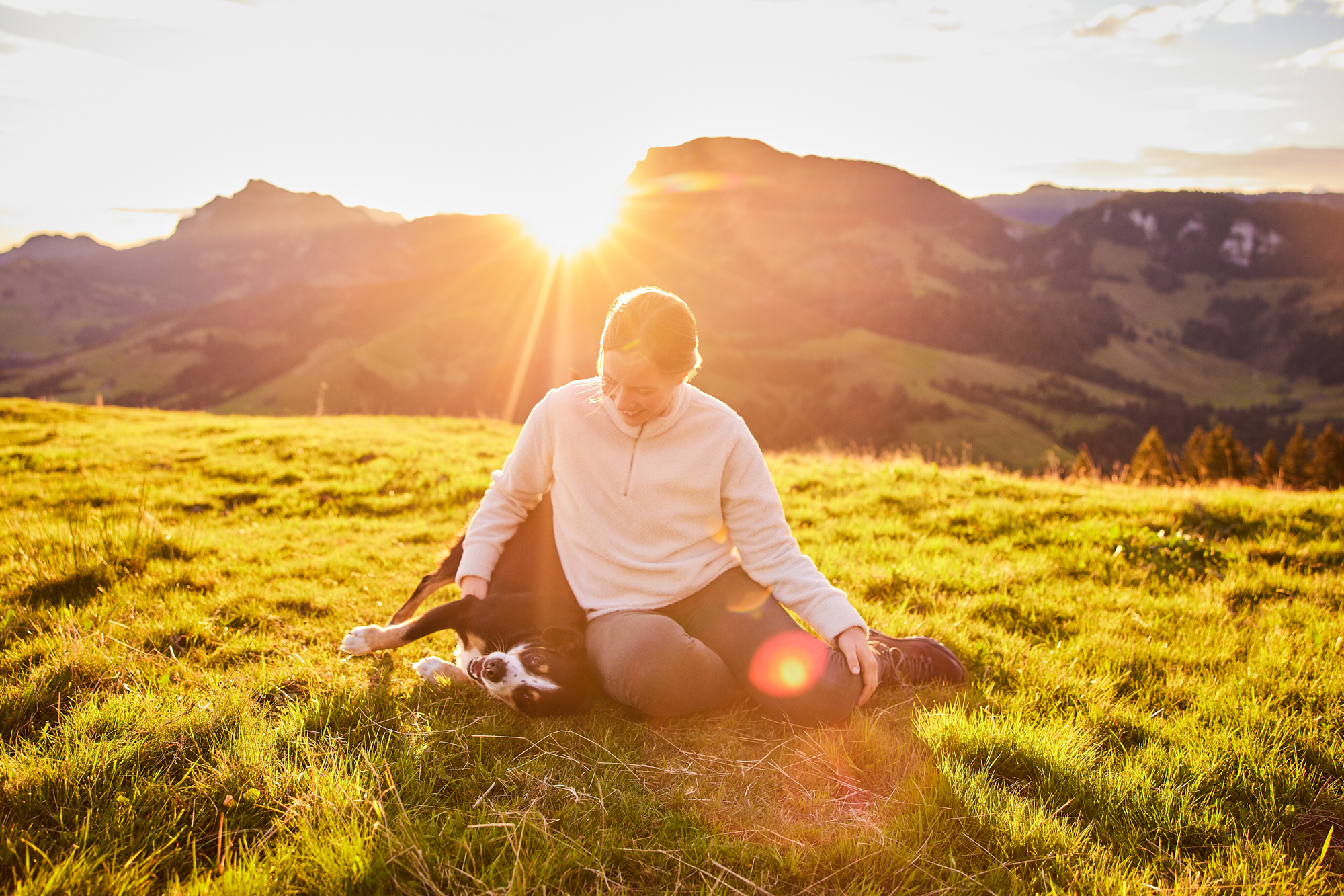 Entlebucher Sennenhund mit Hundebesitzerin bei einem Fotoshooting in Entlebuch in der Schweiz im Sonnenaufgang, professionelles Hunde-Fotoshooting in der Natur